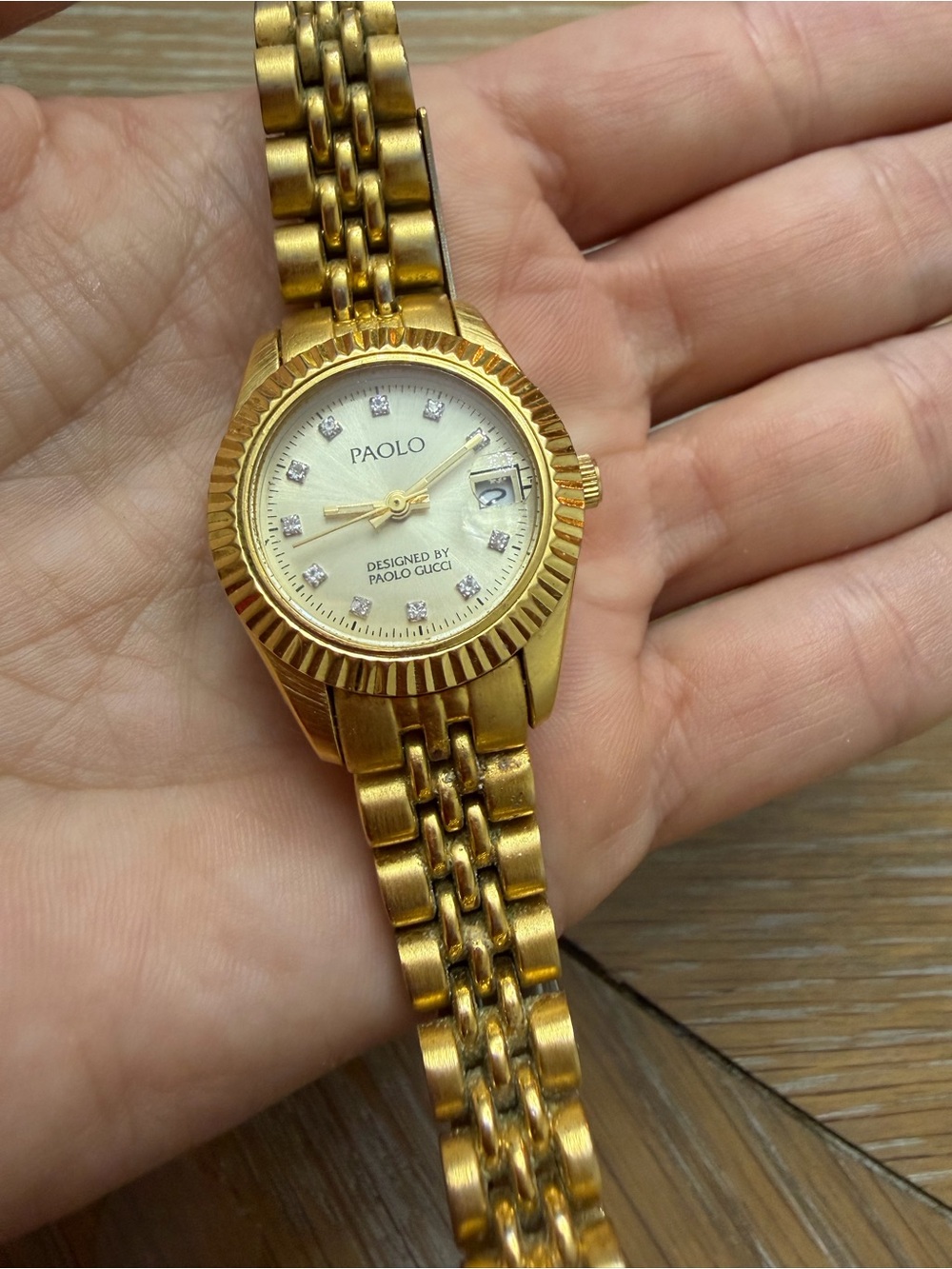 gold-toned Paolo Gucci watch featuring a classic fluted bezel and crystal hour m